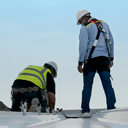 Roofers in fall protection working on a low-slope commercial roof