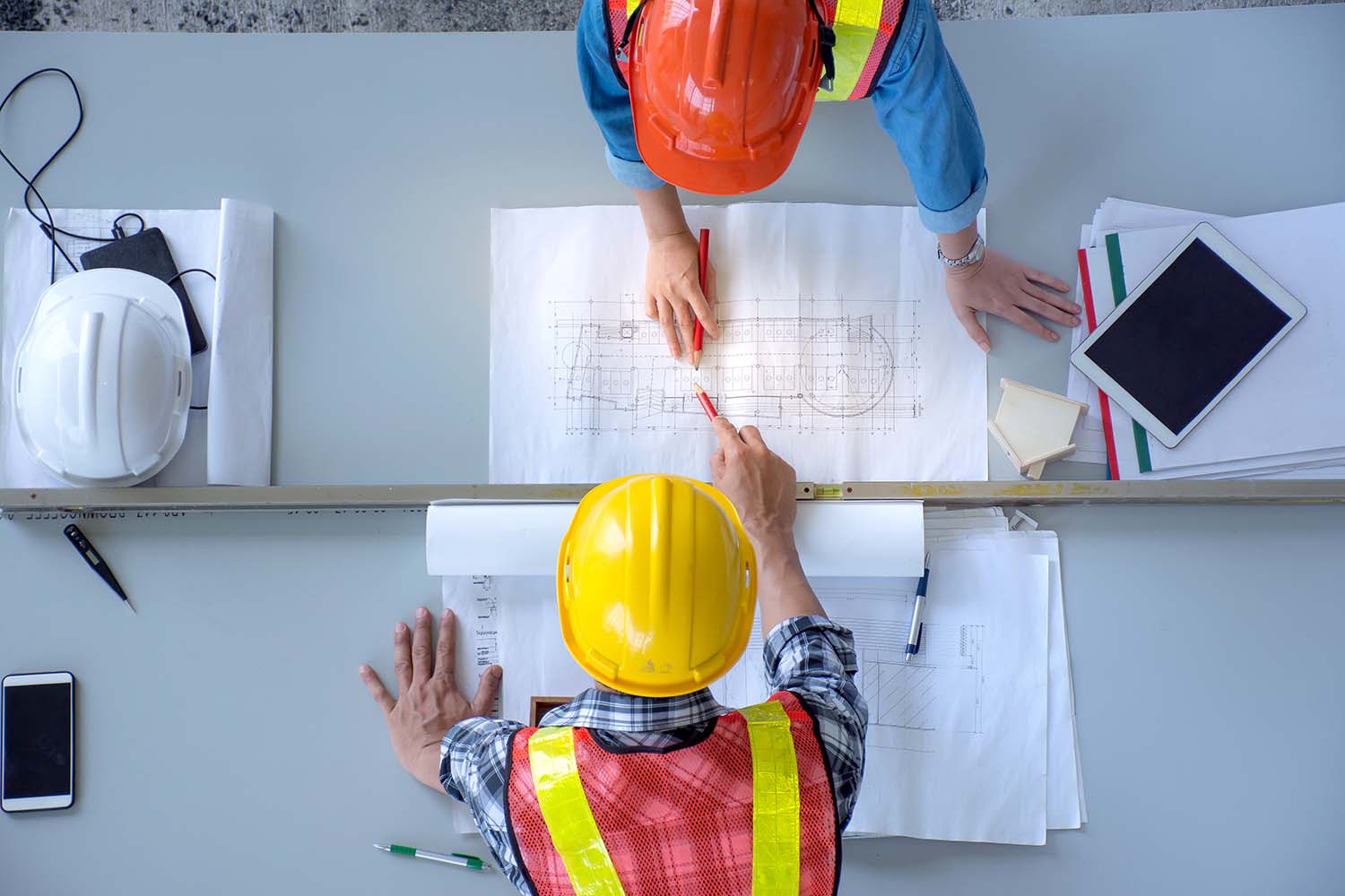 two construction workers looking over blueprints